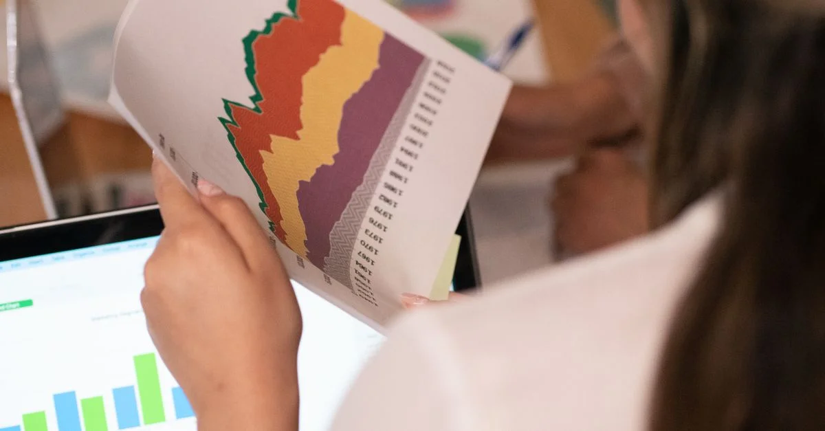Gros plan sur une femme analysant des graphiques et des tableaux colorés dans un bureau.
