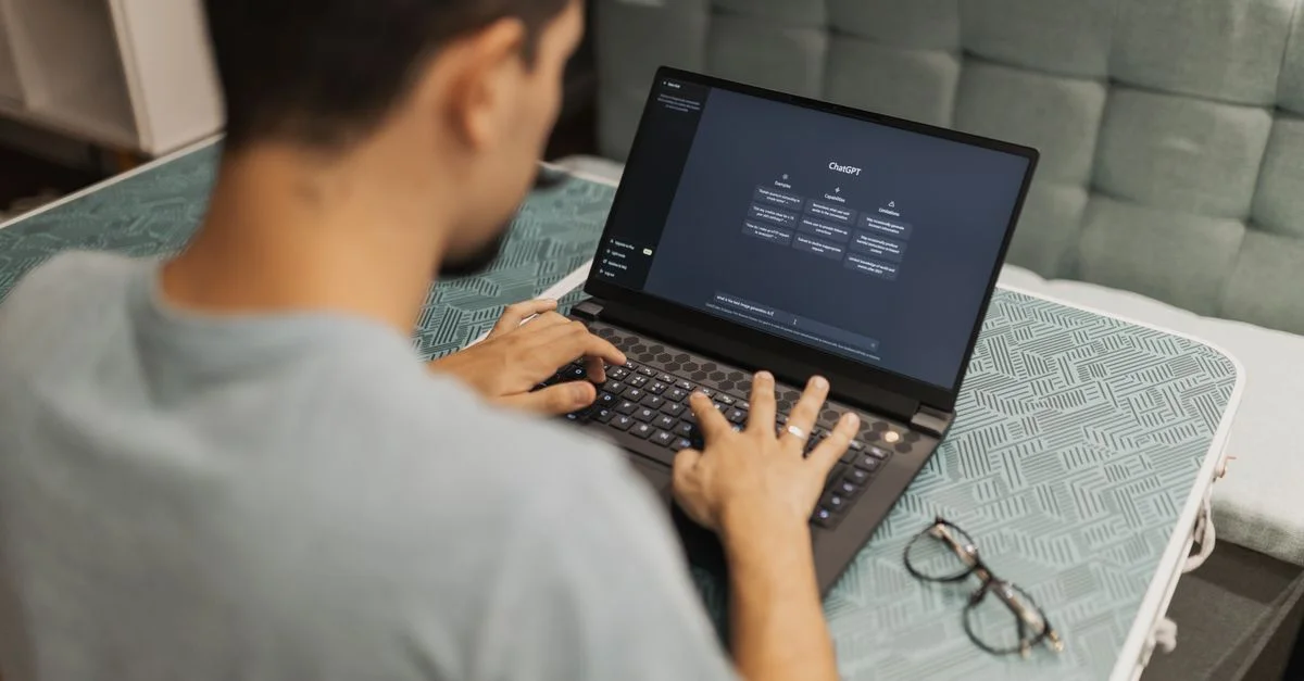Un homme travaillant sur un ordinateur portable affichant l'interface de ChatGPT dans un cadre intérieur.