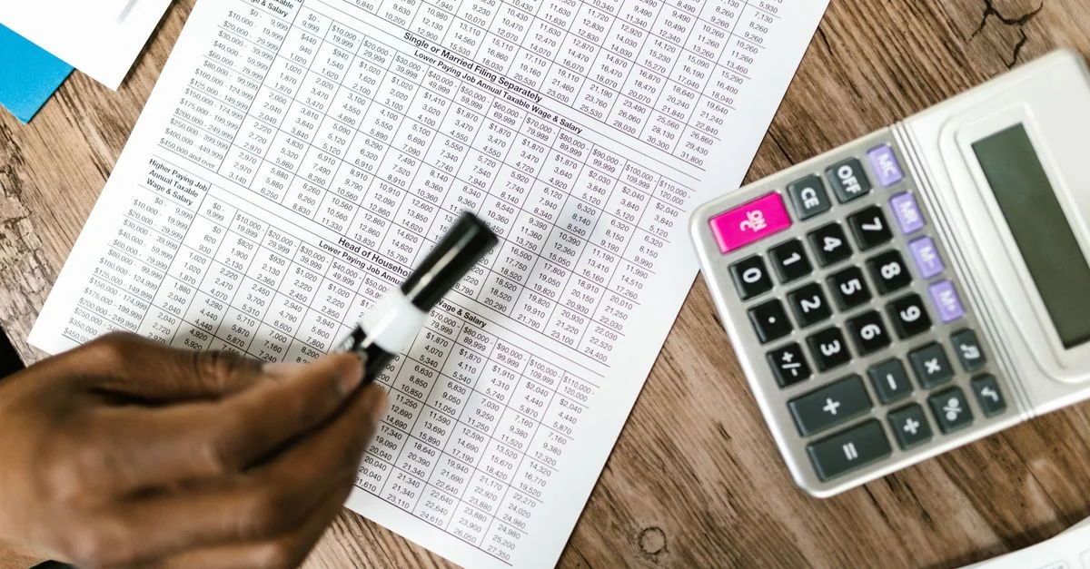 Gros plan sur des documents fiscaux et une calculatrice sur une table en bois, mettant en avant une analyse financière.