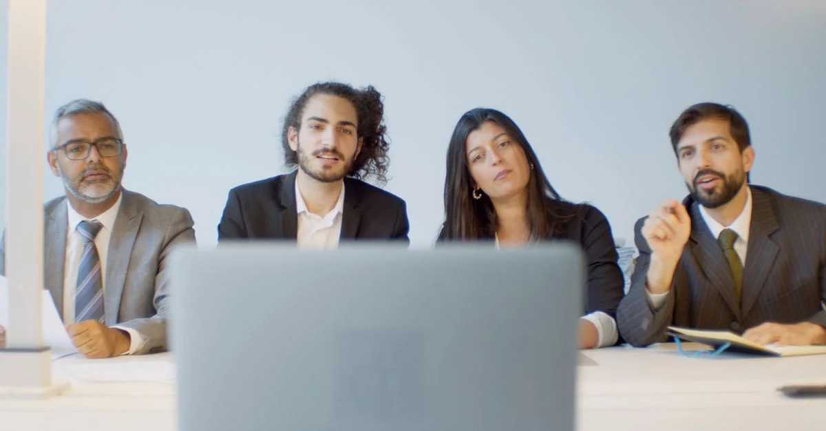 Équipe diversifiée de professionnels en réunion discutant avec un focus sur la configuration de vidéoconférence.